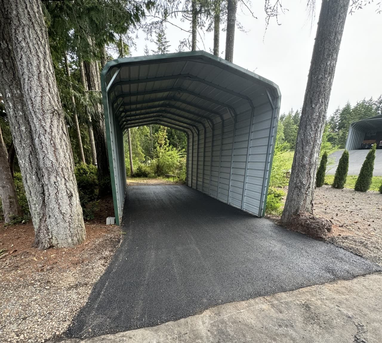 Fresh asphalt driveway through a Northwest carport