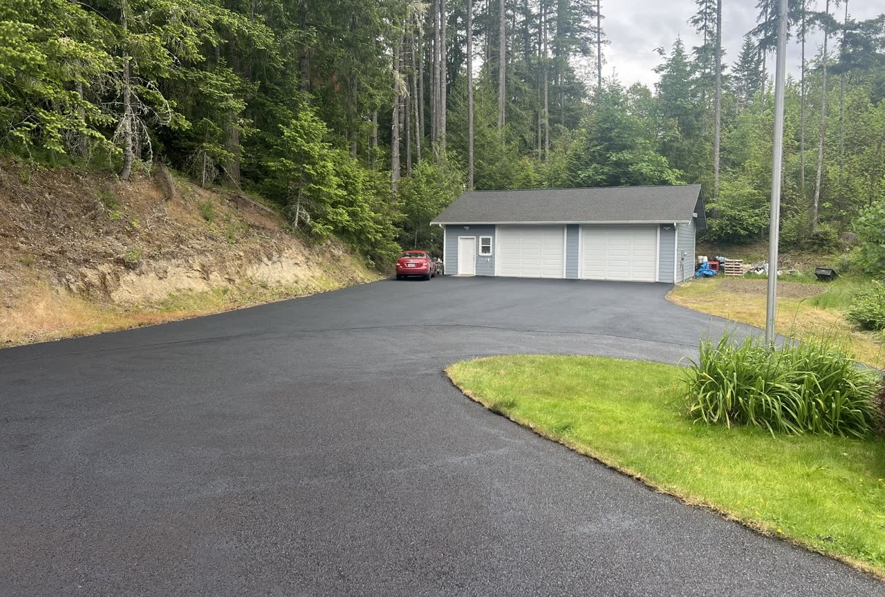 Curved asphalt driveway to a residential garage